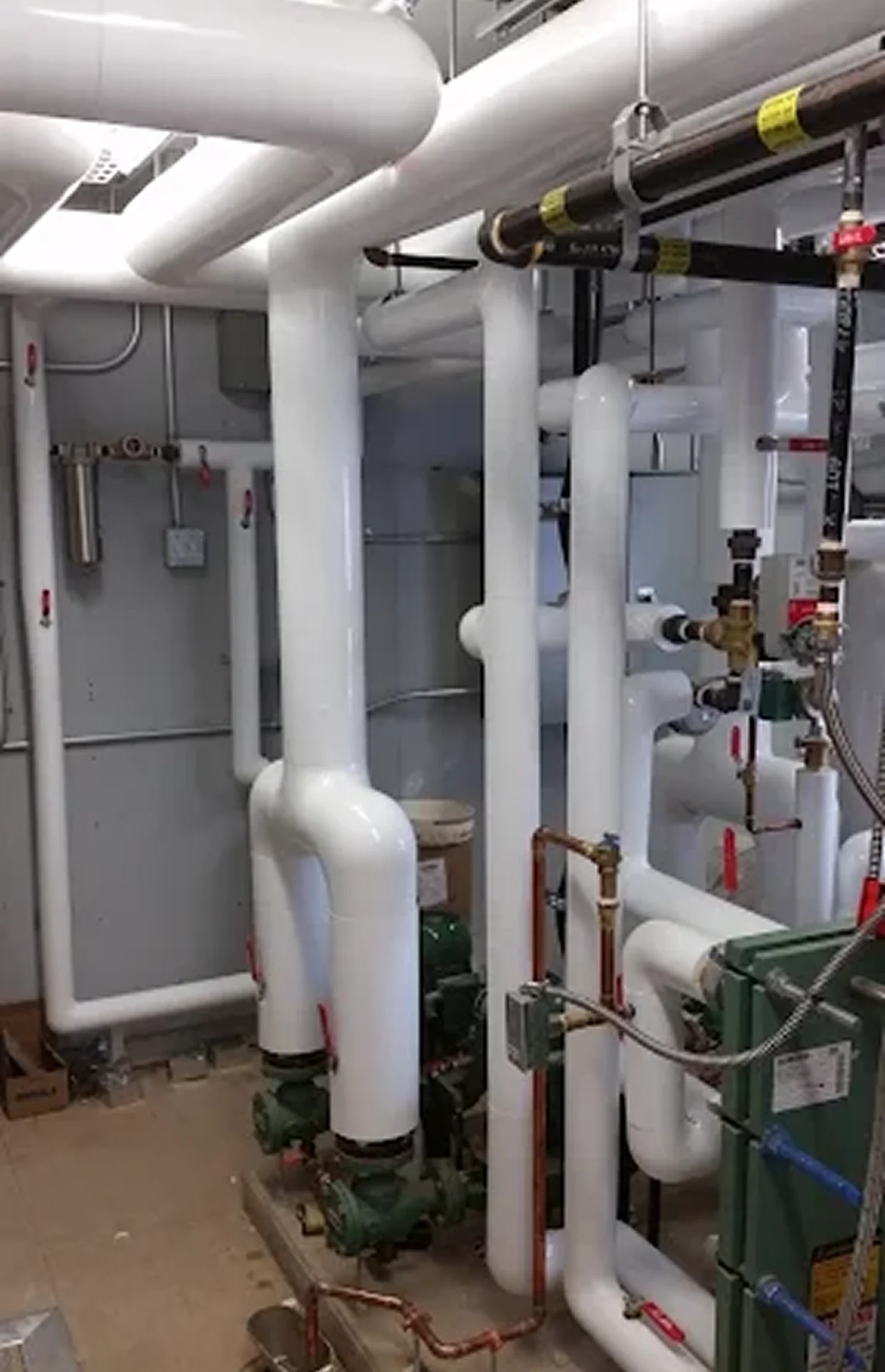 Industrial pipes and valves in mechanical room.