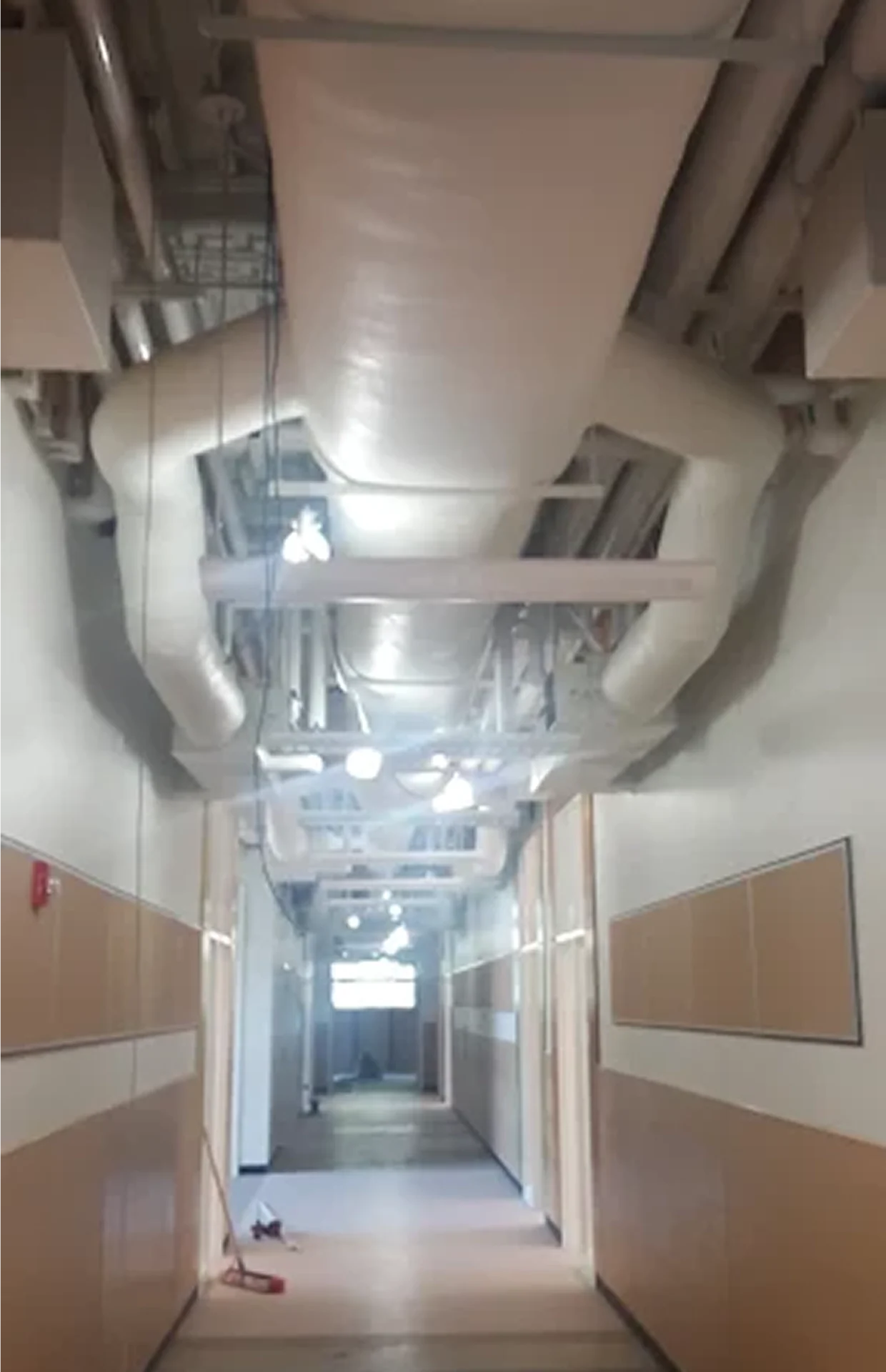 Modern hallway with exposed ceiling pipes.